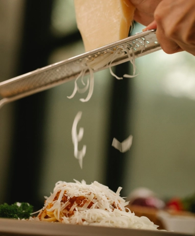 Colocando el queso parmesano al espagueti con salsa boloñesa | Qué Onda