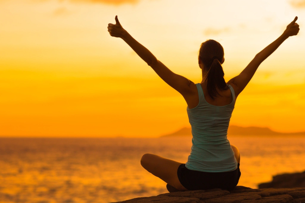 Horóscopo Semanal: Mujer celebrando durante un hermoso atardecer | Qué Onda
