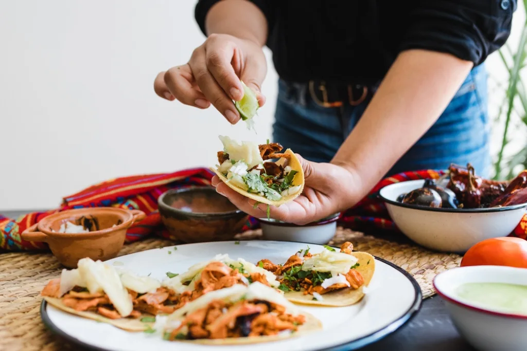 Persona sirviéndose un taco al pastor | Qué Onda  